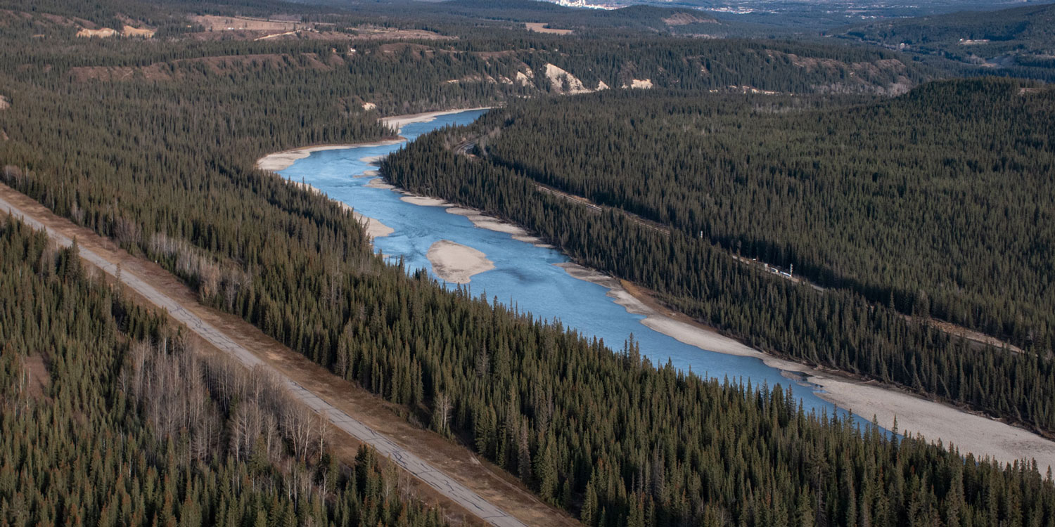 aerial photo of a road beside a large river in the foothills